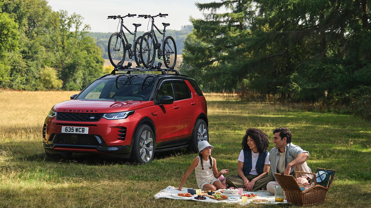 Discovery sports parked with cycle on roof with family