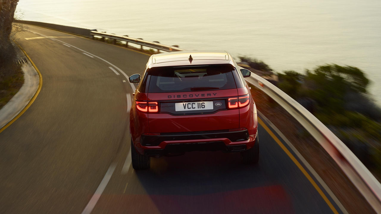 Land Rover Discovery in red driving in seaside background