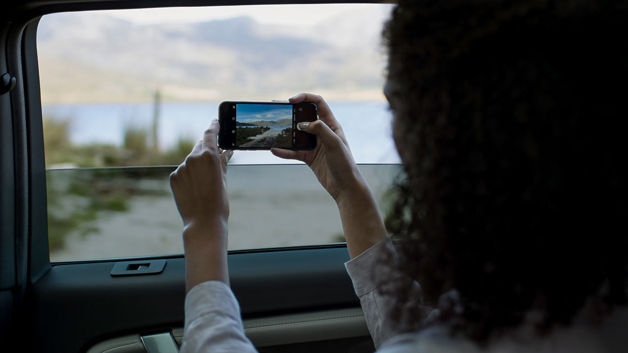 Rear view of girl taking Pictures from car window