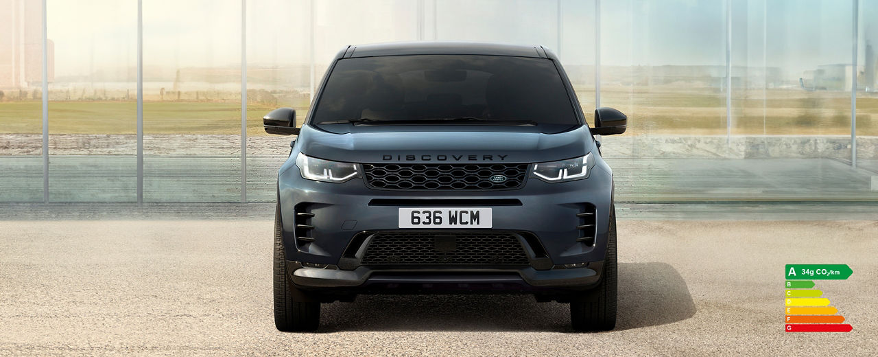 Front view of Discovery Sport in Varesine Blue parked outside of a contemporary house with energy efficiency label A (34g CO2/km).