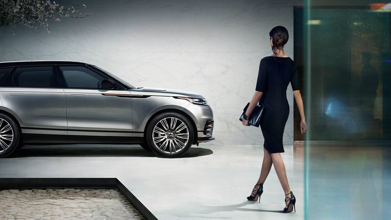 Businesswoman Walking Towards Velar On Showroom