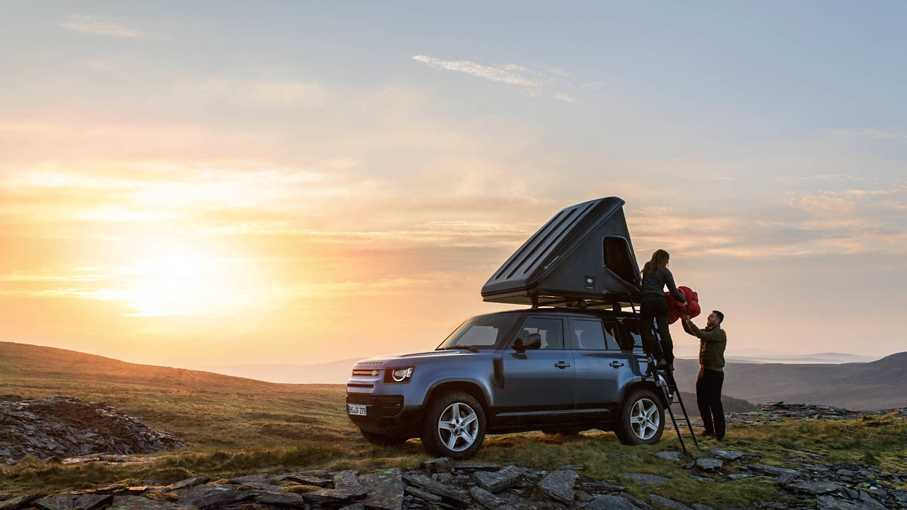 Defender 110 with rooftop tent in the mountains