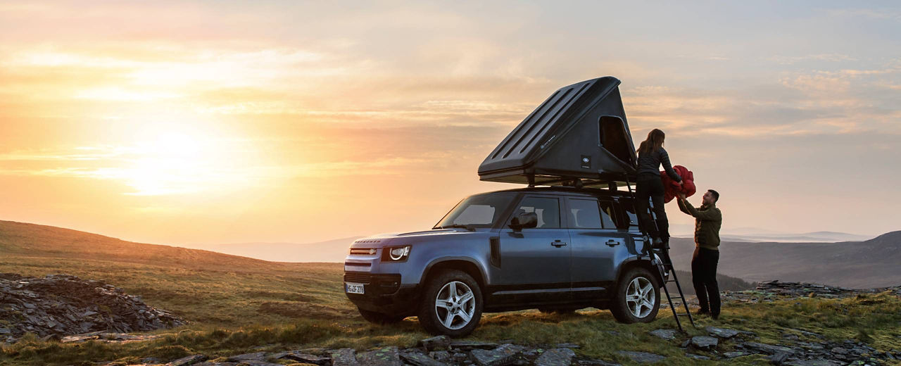 Defender 110 with rooftop tent in the mountains