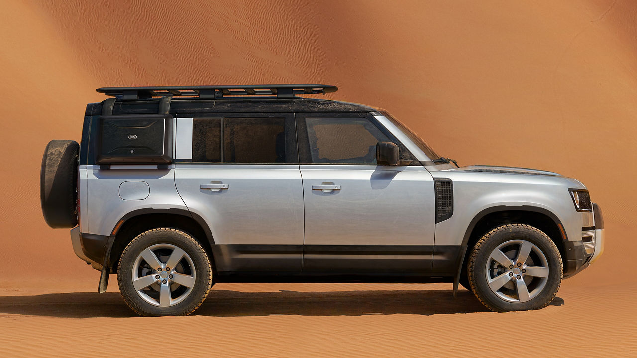 2025 Land Rover Defender 110 in silver parked in front of sand dune