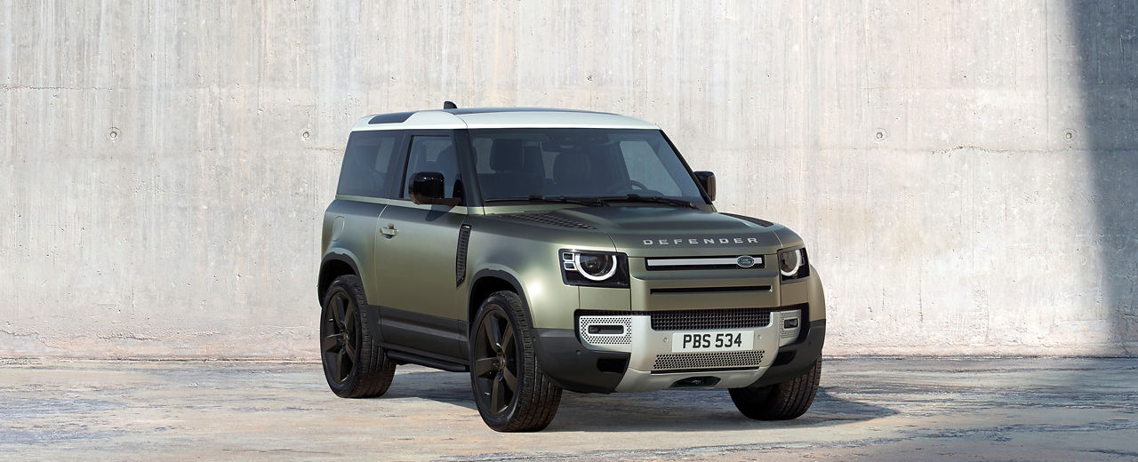 Defender 90 in Pangea Green parked outside.