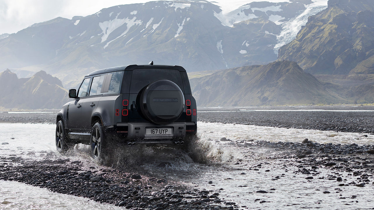 Defender is off roading in the mud of the river