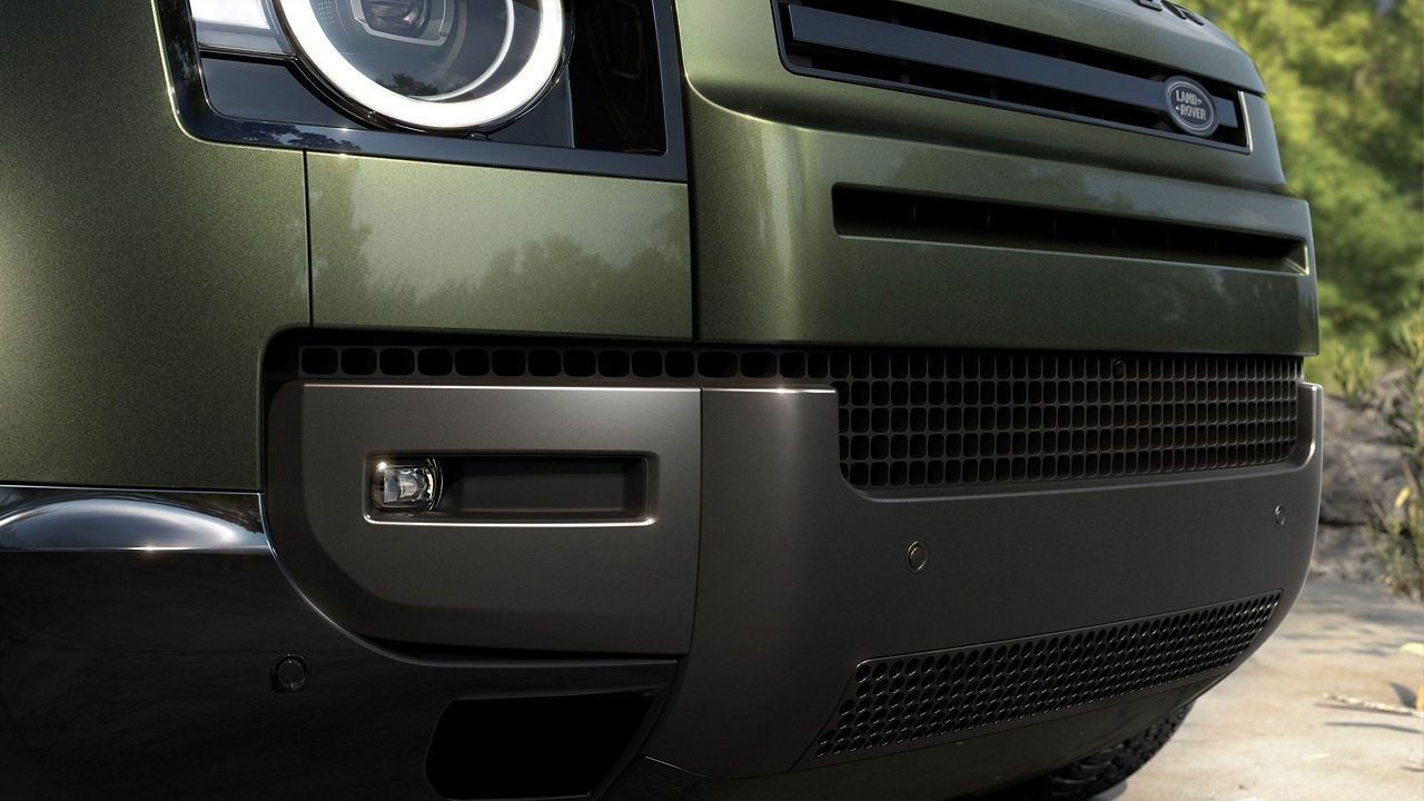 Close-up of the front bumper and headlight of a green Defender.