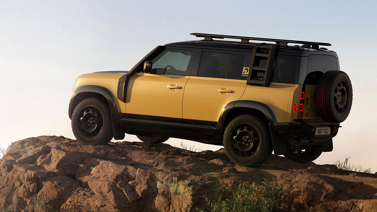 Yellow Defender parked on rocky terrain with a clear side view.