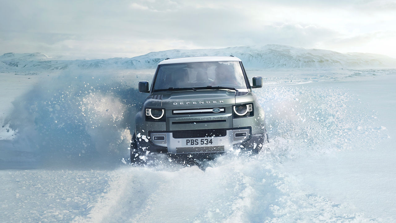 Defender driving over icy mountain