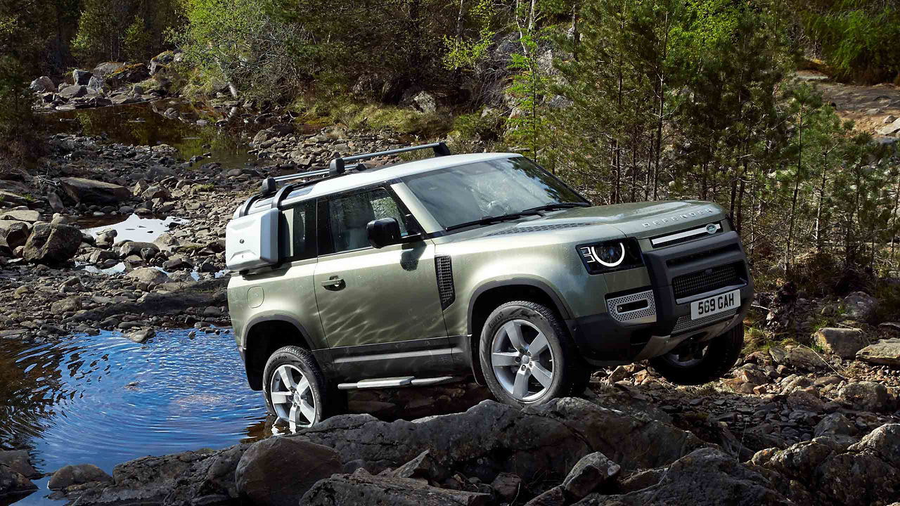 Range Rover Defender in green driving on rocky terrain