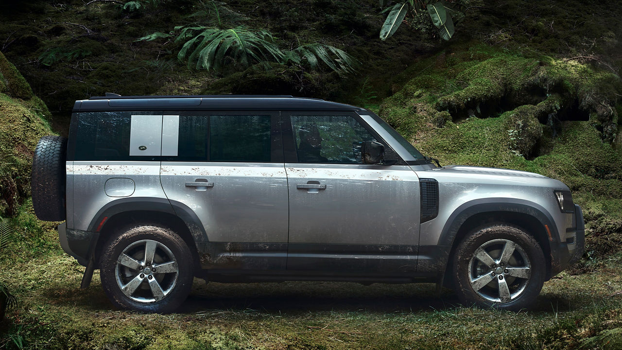 Side Shot Of A Defender On Road Against Lush Trees