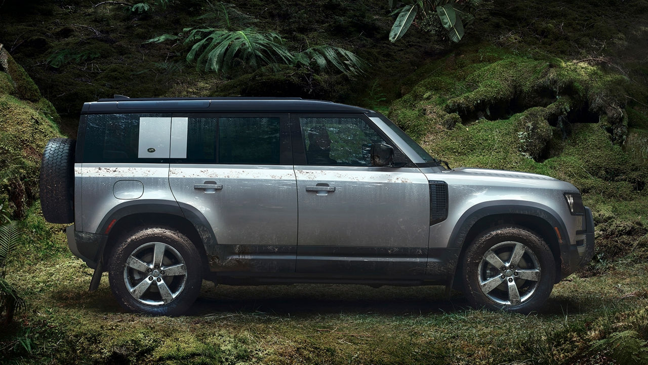 Side Shot Of A Defender On Road Against Lush Trees