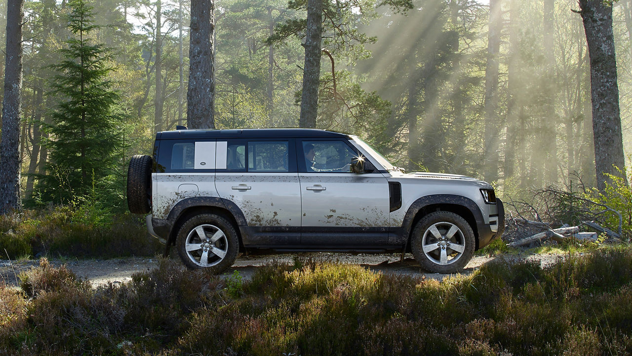 Man is Driving Defender On The Forest Road