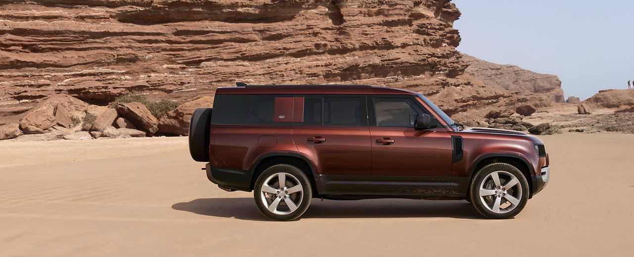 Defender Parked On Sea Beach With A Mountain In Background