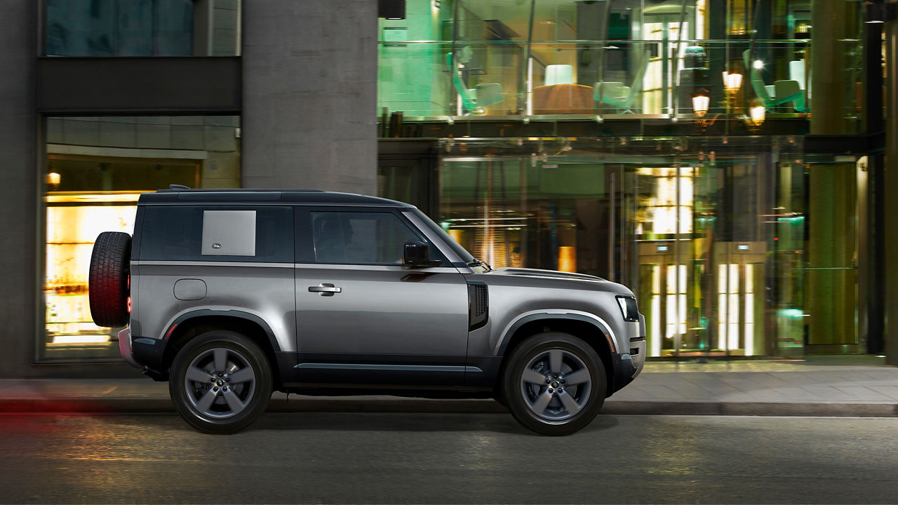 Defender Parked In Front Of Glass Building