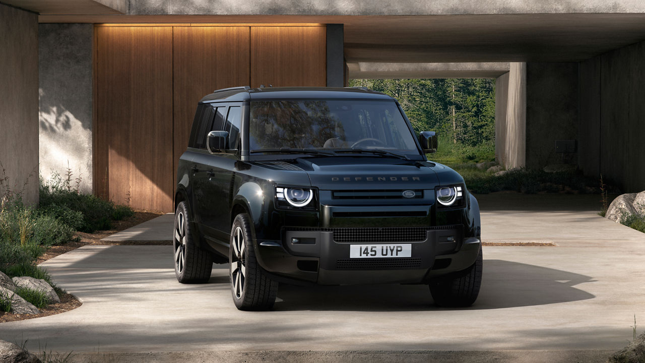 Defender 110 in Tasman Blue parked in front of a modern building.