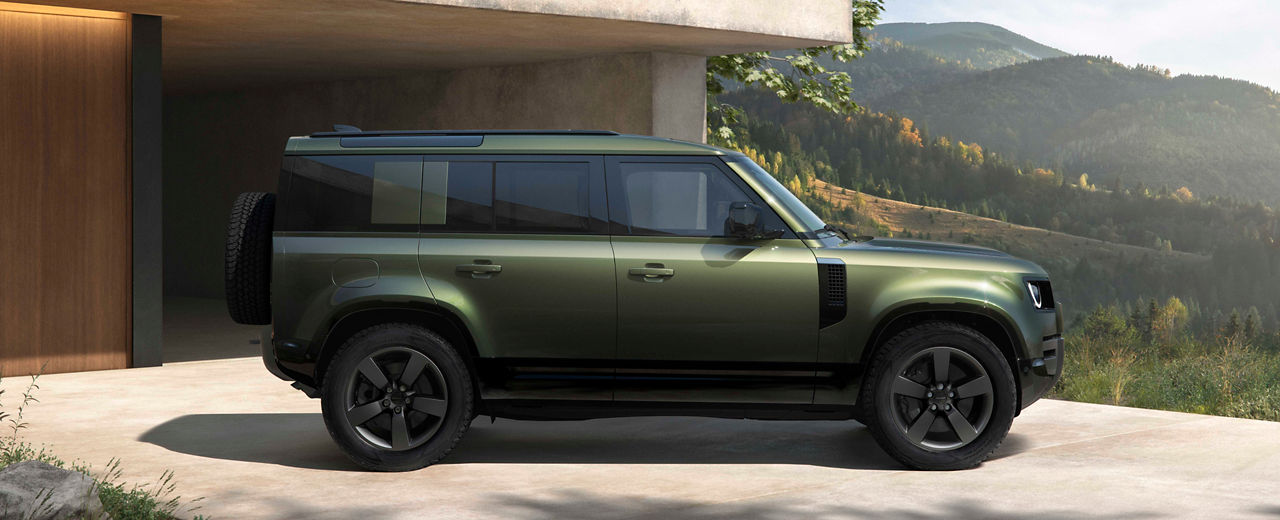 Defender 130 in Woolstone Green parked outside of house in the mountains.