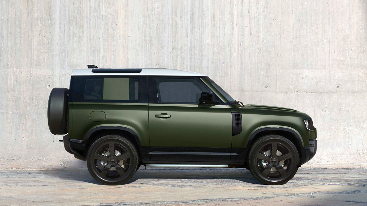 Defender 90 in Woolstone Green parked in front of a wall.