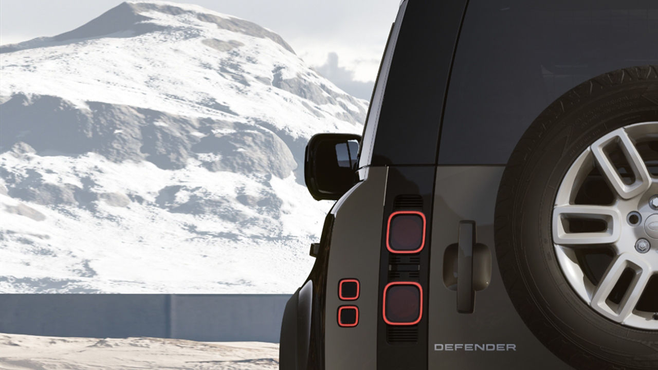 Rear lights of Defender with a spare wheel attached and snowy mountain background