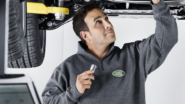 A Land Rover employee servicing the underneath of a car