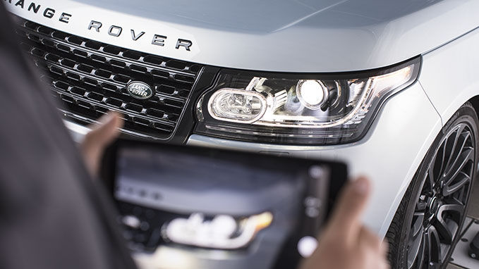 Someone taking a photo of the headlight of a range rover