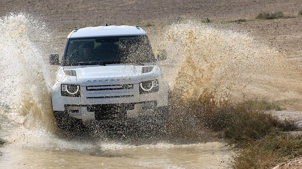 Land Rover Defender moving on a Mud Water Forest Road