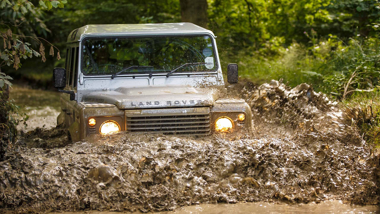 Defender crossing mud water on the test road in forest area