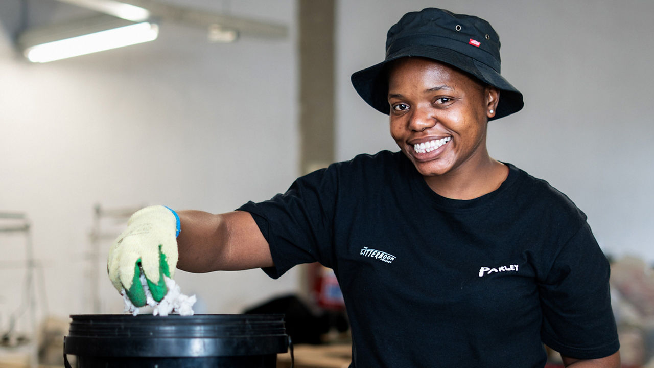 Smiling person sorting waste into a bin.