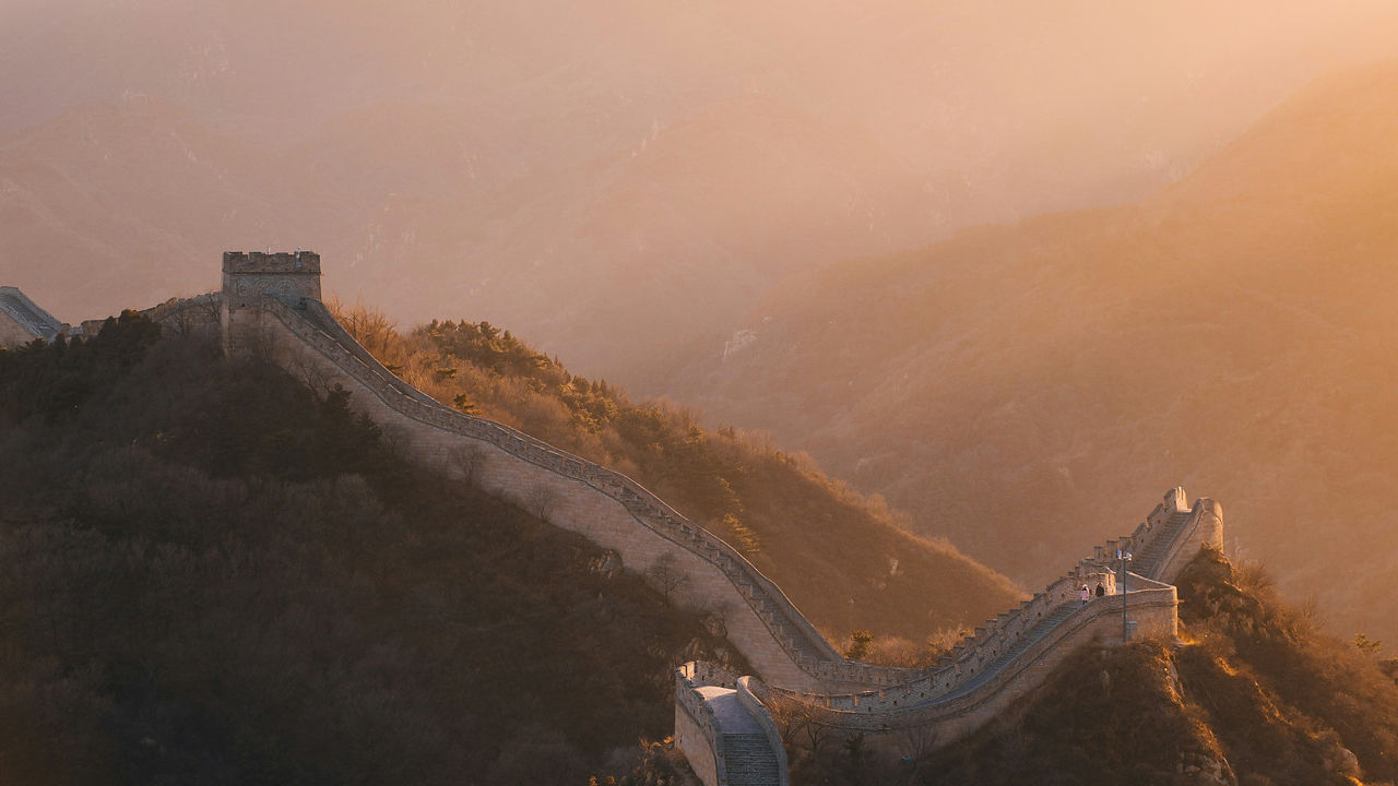 Great wall of China winding over hills at sunset.