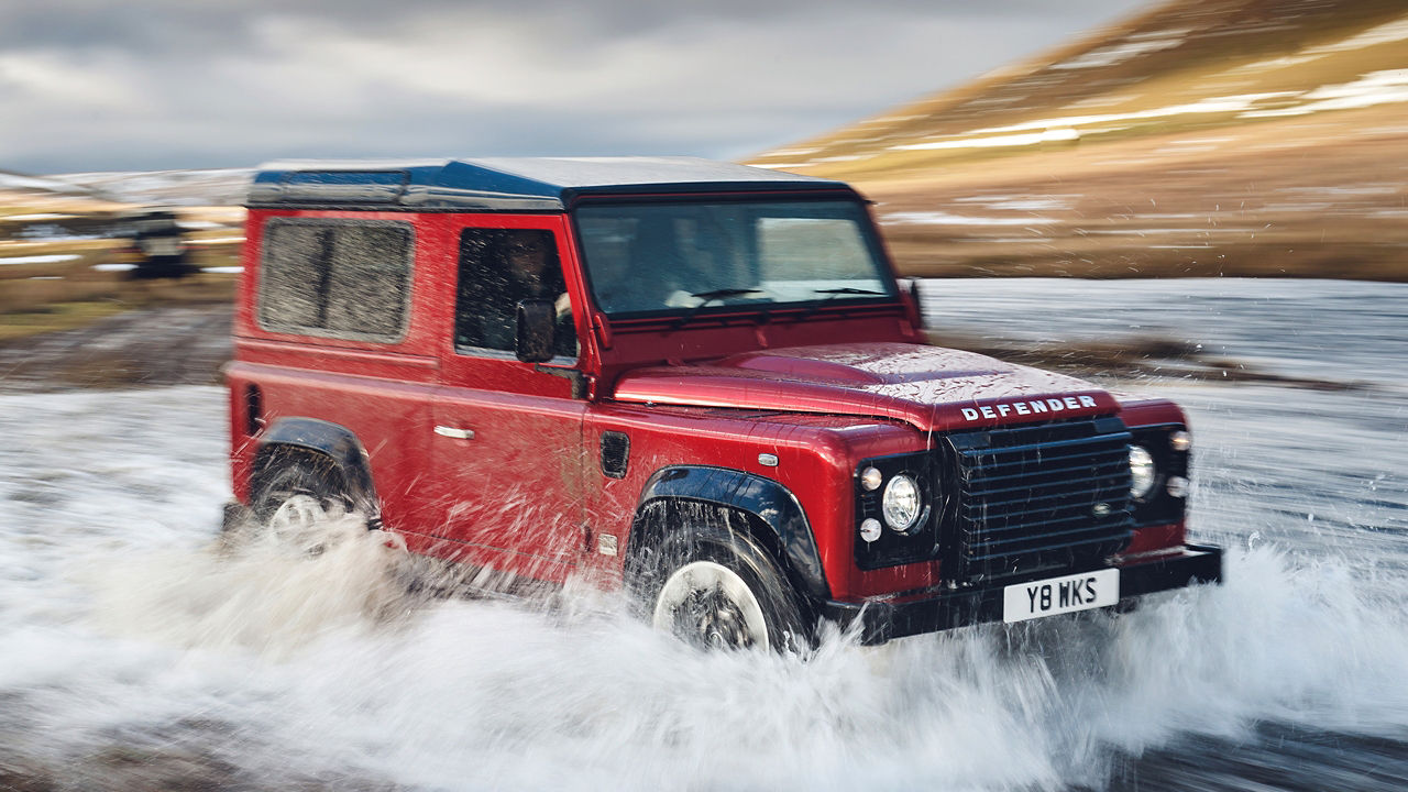 Classic Defender crossing water on the test road in hilly area