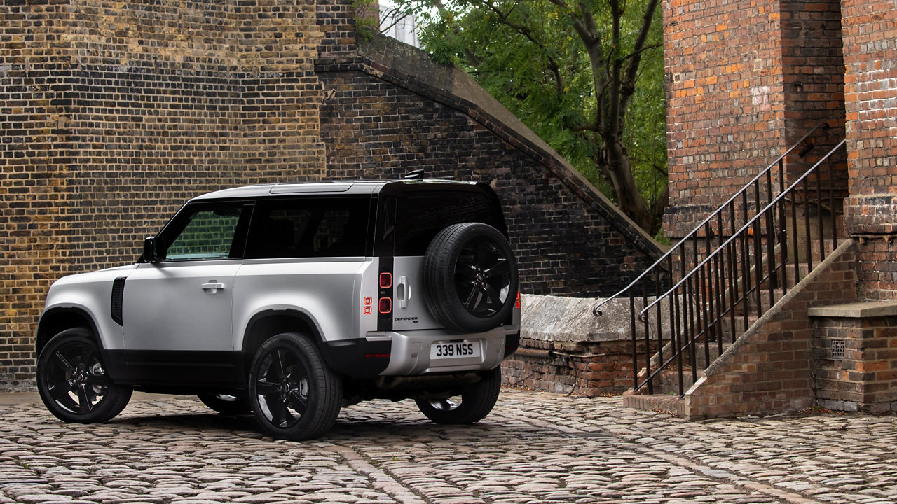 Parked defender on cobble stones near half brick wall building