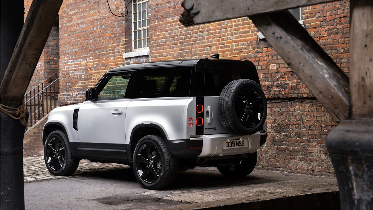 Parked defender on cobble stones near half brick wall building