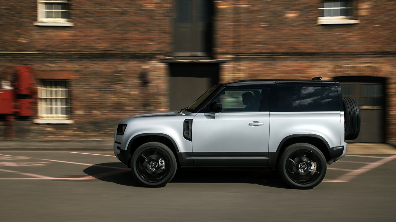 Defender running on road beside cobble stones building