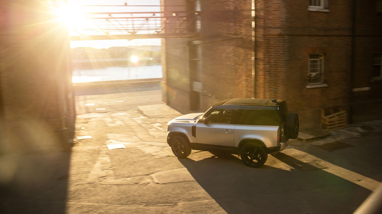 Parked defender at sunset near half brick wall building