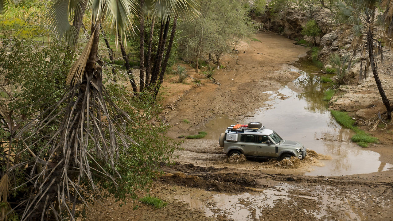 Defender drive crosses the mud obstacle on the forest off-road