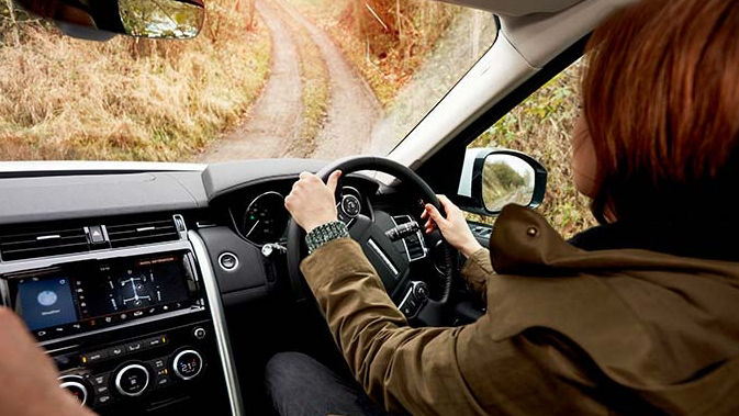 View inside the cockpit of a Range Rover driving on a dirt road