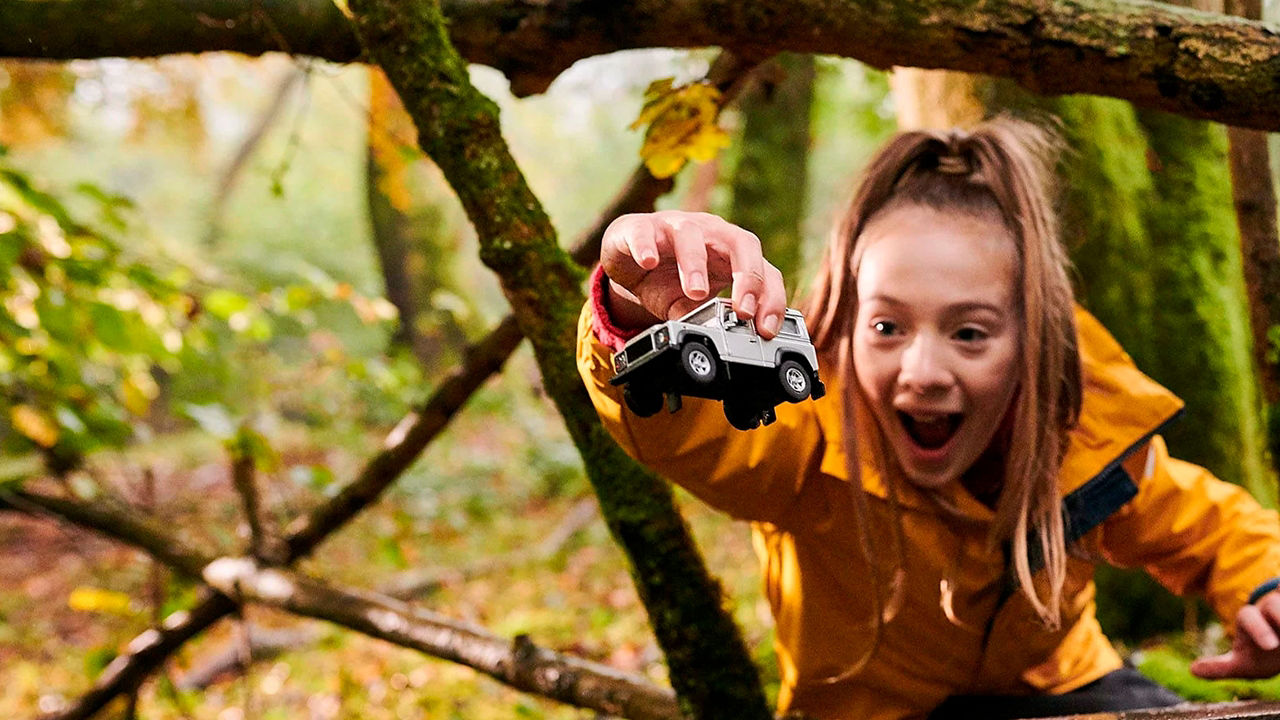 A girl playing with Land Rover toy car