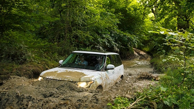 Range Rover driving through water in a forest 