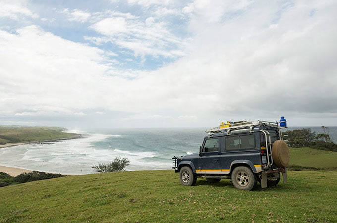 Classic Land Rover parked on grass by the sea