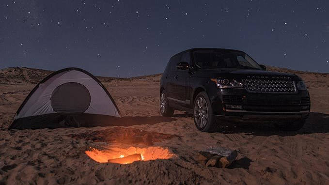 Black Range Rover in desert with stars in sky