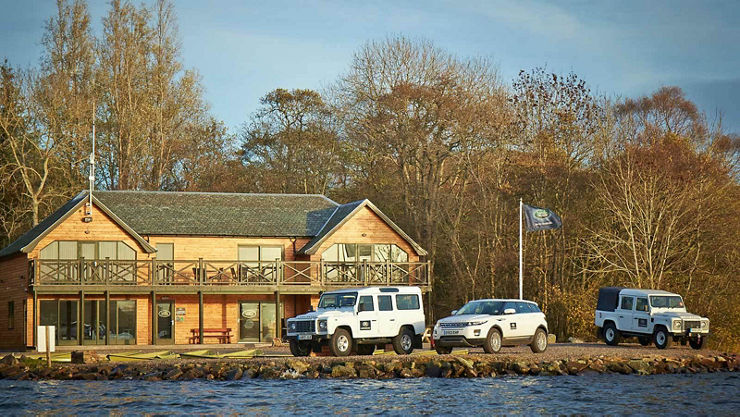 A Range Rover Evoque parked next to Classic Land Rover Defender vehicles outside house 