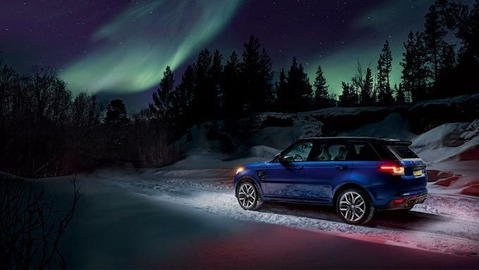 Blue Range Rover driving with Northern Lights