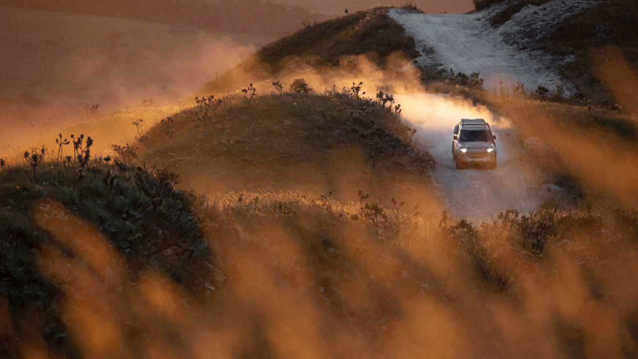 Defender driving down a road