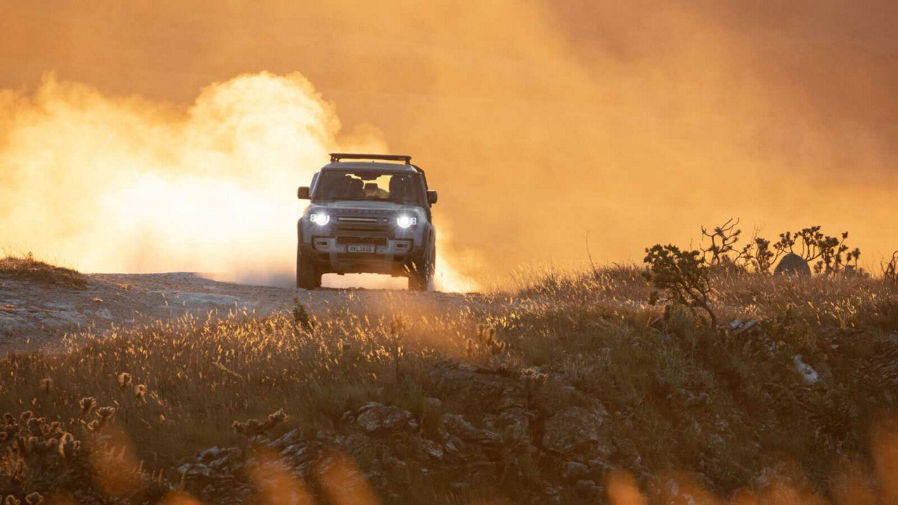Defender driving towards camera with headlights on