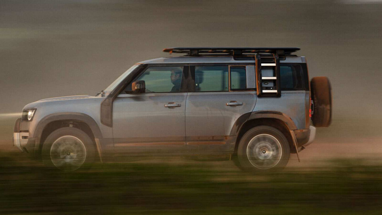 Defender driving fast on a road