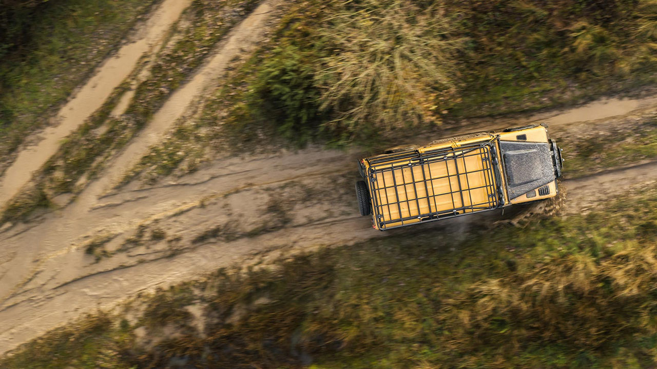 View from above of Land Rover Defender Works V8 Trophy driving on dirt road