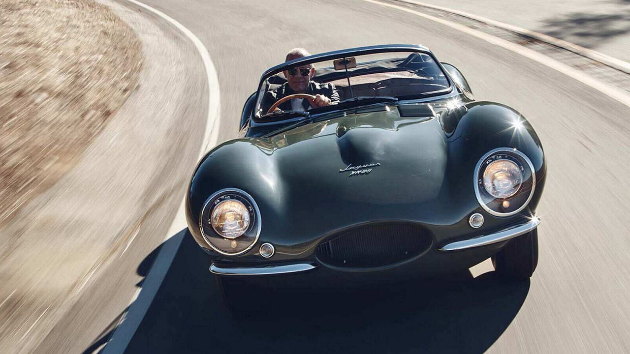 Jaguar XKSS in green driving round a bend.