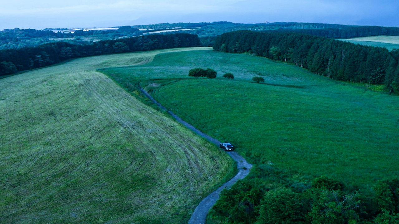 Hiro Kimura in a Jaguar I-Pace in fields