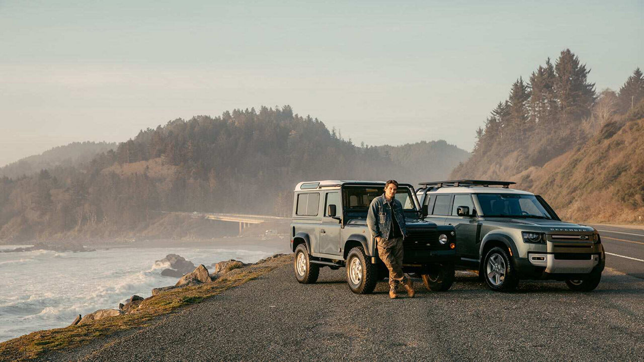 John Mayer standing next to two Land Rover Defender