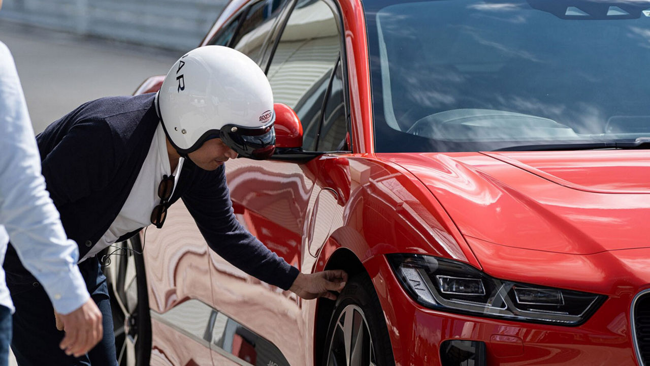 Jun Tada is checking the tyres of a Jaguar I-Pace vehicle
